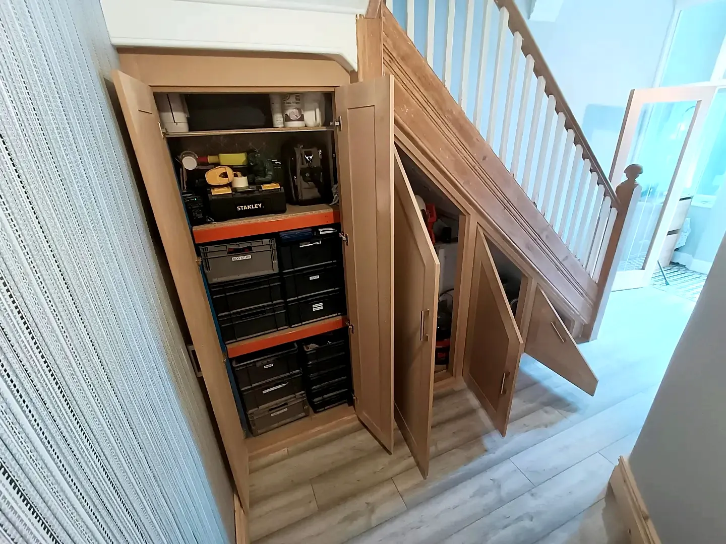 Under-stairs cupboards open, fitted out with shelving
