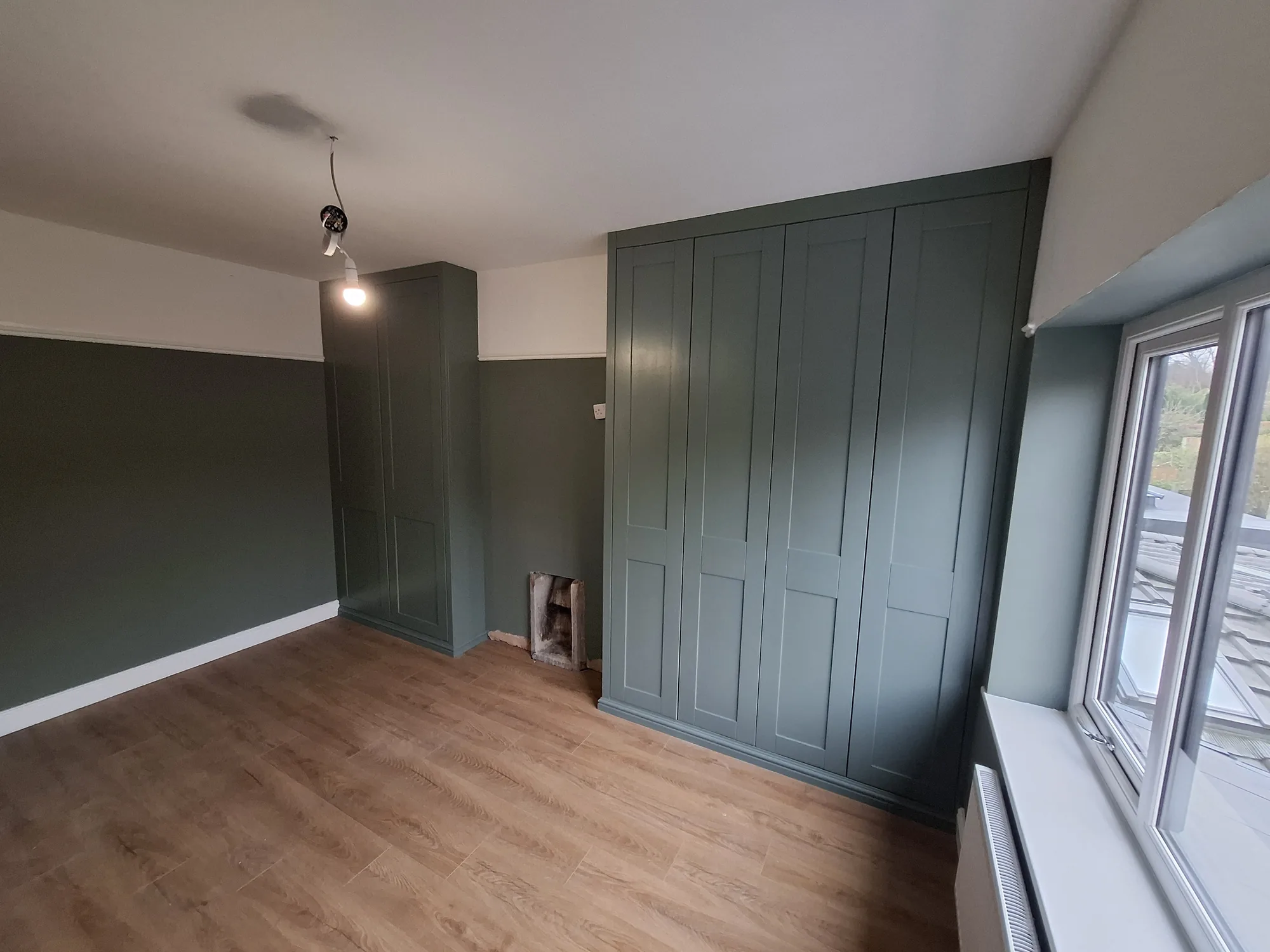 Full-height fitted wardrobe run beside the window