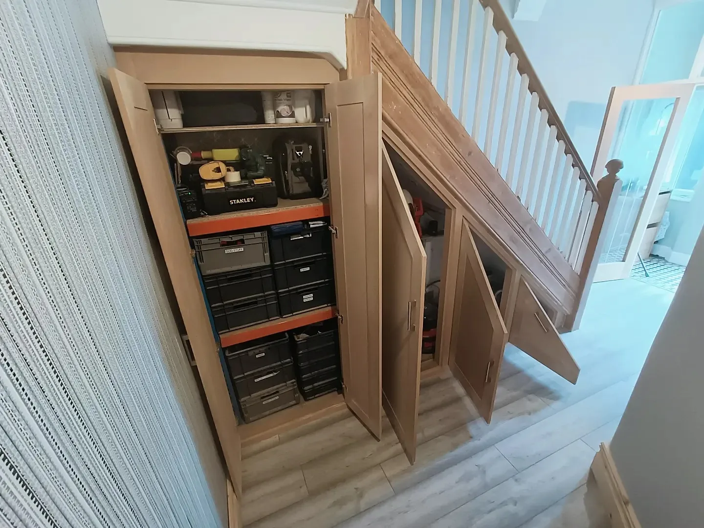 Under-stairs cupboards open, fitted out with shelving