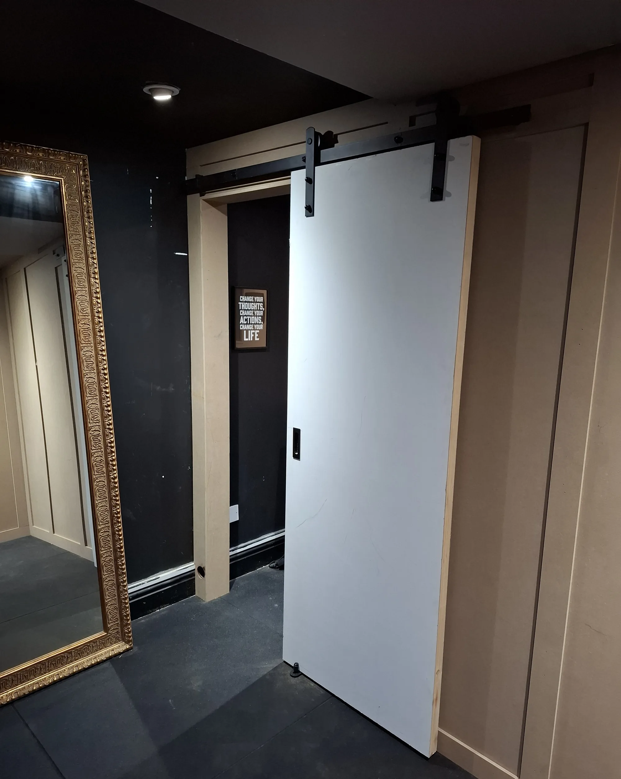 Sliding barn door on a black track in a home gym